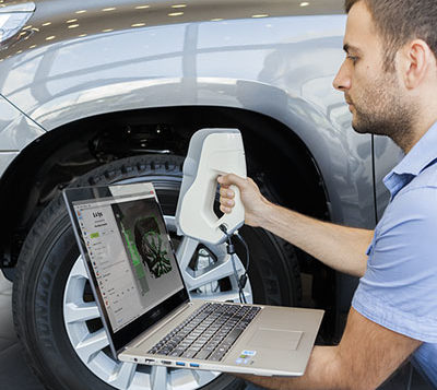 man using a 3D sanner to scan car part